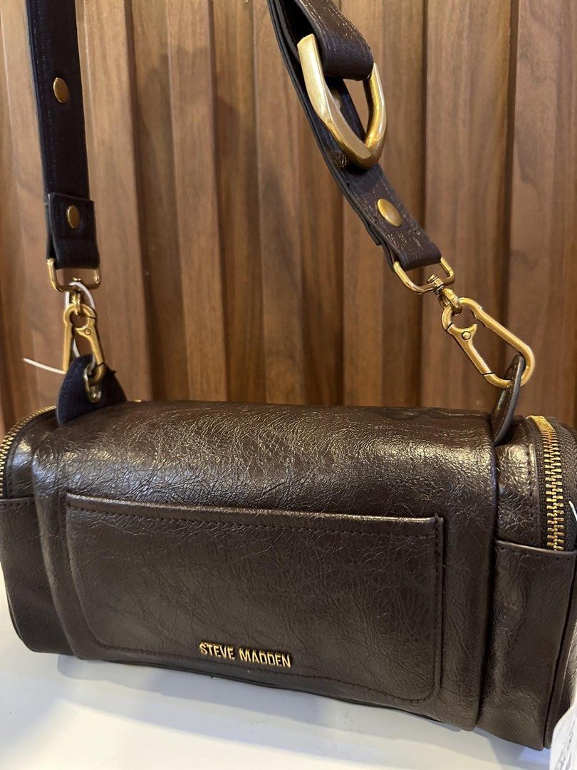 Steve Madden Brown Barrel Bag with Gold Hardware (Category: Luxury Bags & Wallets) located in Makati City. Submitted by sebastiene (Listing ID 1451785834, Image 3). Description: - Cool barrel-shaped bag from Steve Madden - Dark brown color with a textured finish - Stylish gold hardware details (zippers, chain strap accents) - Convenient front pocket - Detachable crossbody strap for versatile wear - Ideal for everyday use or a night out.