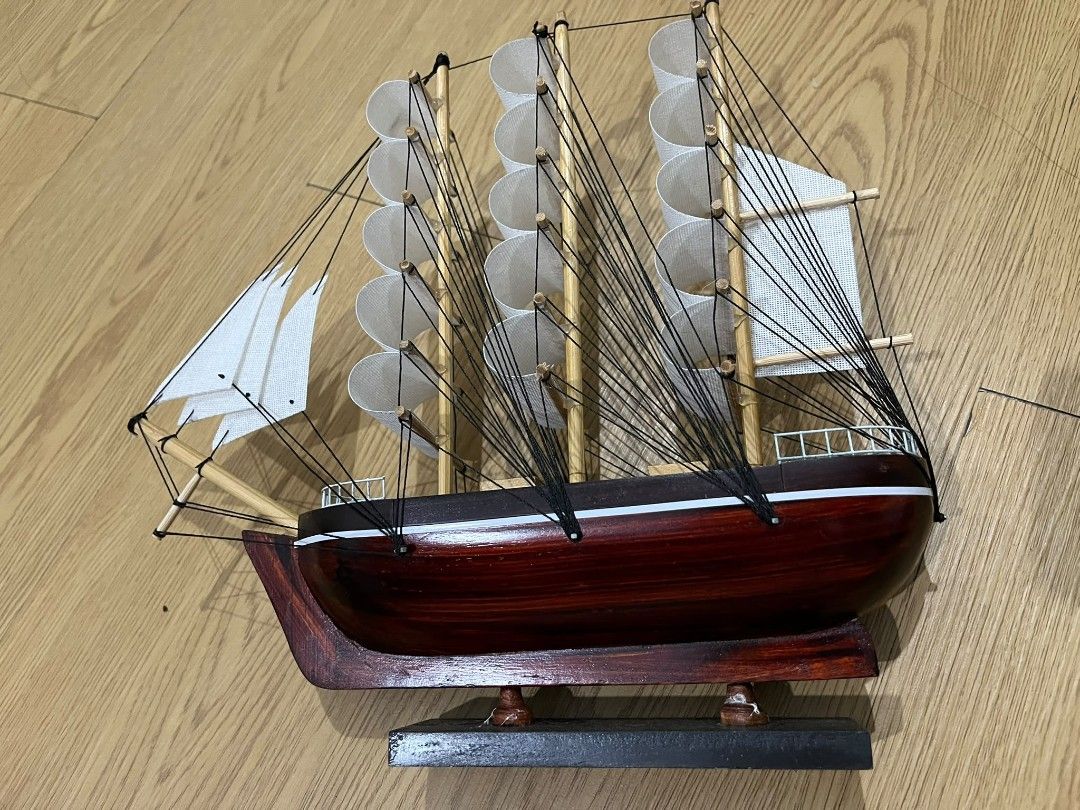 Wooden Tall Ship Model with White Sails (Category: Other Home Decor) located in Kuala Lumpur. Submitted by mychanelcelineoffici896 (Listing ID 1451882985, Image 2). Description: - Detailed wooden model of a tall ship - Features multiple white sails and intricate rigging - Deep reddish-brown hull - Comes with a sturdy wooden display stand - Ideal for shelf or desk decoration - Adds a charming nautical touch to any space.