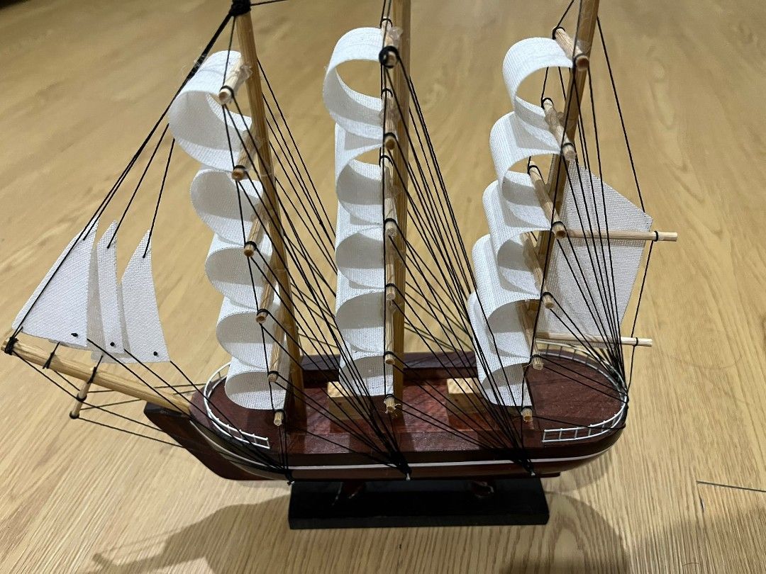 Wooden Tall Ship Model with White Sails (Category: Other Home Decor) located in Kuala Lumpur. Submitted by mychanelcelineoffici896 (Listing ID 1451882985, Image 3). Description: - Detailed wooden model of a tall ship - Features multiple white sails and intricate rigging - Deep reddish-brown hull - Comes with a sturdy wooden display stand - Ideal for shelf or desk decoration - Adds a charming nautical touch to any space.