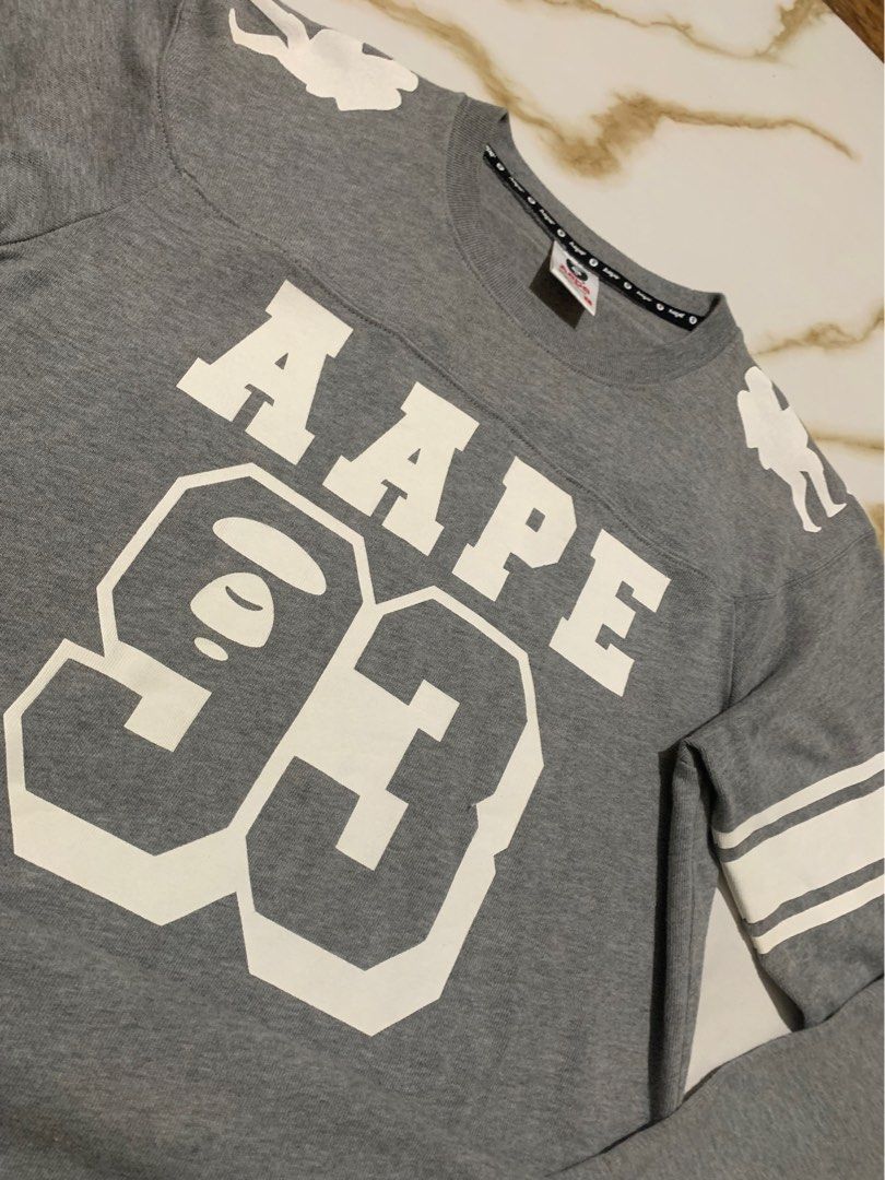AAPE BY A BATHING APE Grey Graphic Sweatshirt Size L (Category: Coats, Jackets and Outerwear) located in Iloilo. Submitted by johnpullan30303 (Listing ID 1451935151, Image 2). Description: - Grey AAPE sweatshirt - Size: L - Front graphic: 'AAPE 93' - Sleeve detail: White stripes - Shoulder detail: Ape graphics - Back detail: 'AAPE BY A BATHING APE' text - Please check photos for detailed condition..