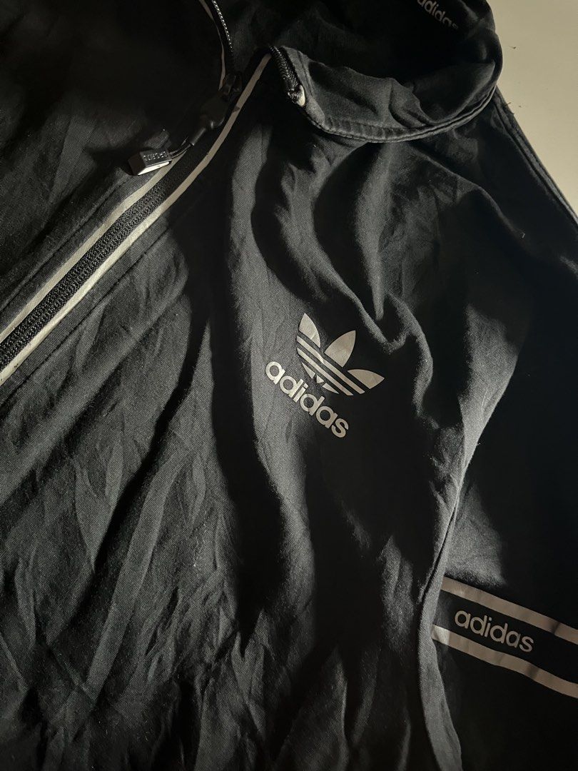 Adidas Zip Up Jacket (Category: Coats, Jackets and Outerwear) located in Santa Ana. Submitted by rlave (Listing ID 1452000313, Image 2). Description: Preloved Adidas Originals black full-zip track jacket, featuring the classic embroidered/printed Trefoil logo on the chest, “adidas” branding repeated along the collar and sleeve trims, and zippered side pockets. Ribbed collar and cuffs, comfortable relaxed fit — great for layering or everyday casua