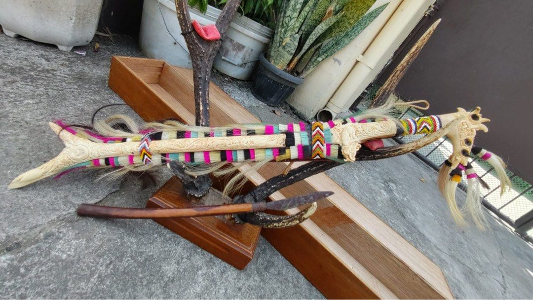 Antique Tribal Knife (Category: Vintage Collectibles) located in Cainta. Submitted by danica010314 (Listing ID 1452036915, Image 2). Description: This item is a traditional Dayak Mandau sword from Borneo, featuring a detailed carved hilt made of deer horn and a sheath adorned with colorful fabrics and goat hair.- Unique decorative knife set - Features carved bone handles - Colorful woven accents - Sharp blades with a rustic finish - Ideal for col