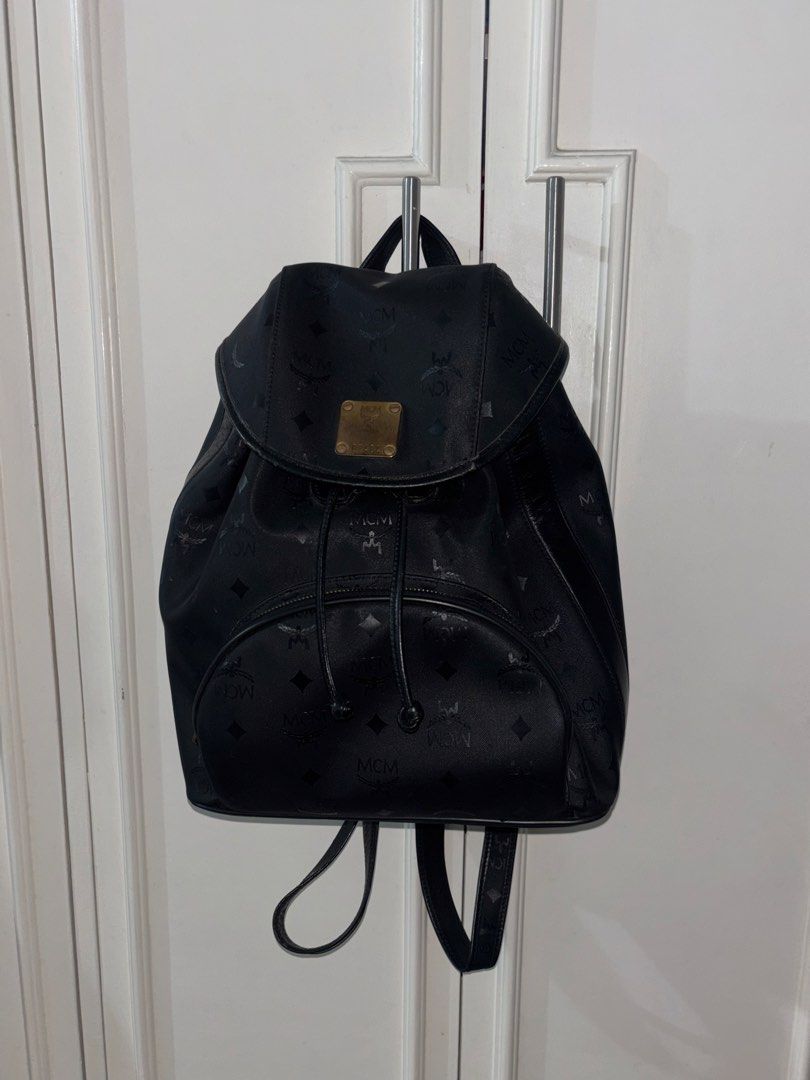 Authentic Vintage MCM Black Monogram Nylon Backpack with Gold Hardware Plaque (Category: Luxury Bags & Wallets) located in Masantol. Submitted by duhitsangelene (Listing ID 1452036368, Image 2). Description: Product Details: Brand: MCM (Modern Creation München) Color: Black with subtle jacquard monogram print Material: Durable nylon / canvas body with leather trim Closure: Magnetic flap over drawstring closure Pockets: One front zippered compartm