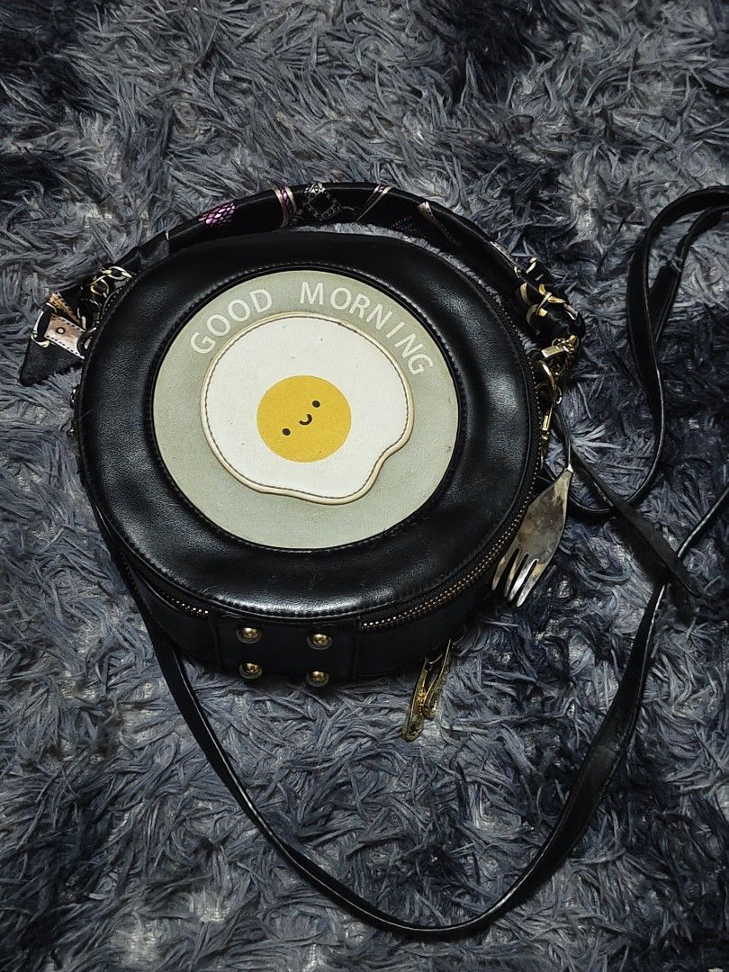 Cute Fried Egg Round Japanese Bag with Scarf Handle (Category: Cross-body Bags) located in Manila. Submitted by querobin11 (Listing ID 1452039972, Image 2). Description: - Adorable round bag with a fun fried egg design. - Features 'Good Morning' text for a cheerful vibe. - Stylish scarf-wrapped handle. - Includes a long strap for versatile carrying options. - Accented with elegant gold hardware. - Adds a playful and unique touch to any outfit. RF