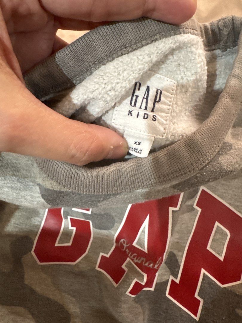 Gap Kids Camo Sweatshirt - Size XS (Category: Babies & Kids Fashion) located in San Pablo. Submitted by ShopbyLiz (Listing ID 1451900909, Image 3). Description: - Grey camouflage sweatshirt from Gap Kids - Features classic red Gap logo - Crew neck, long sleeves - Soft interior lining for comfort - Perfect for everyday wear - Size XS.
