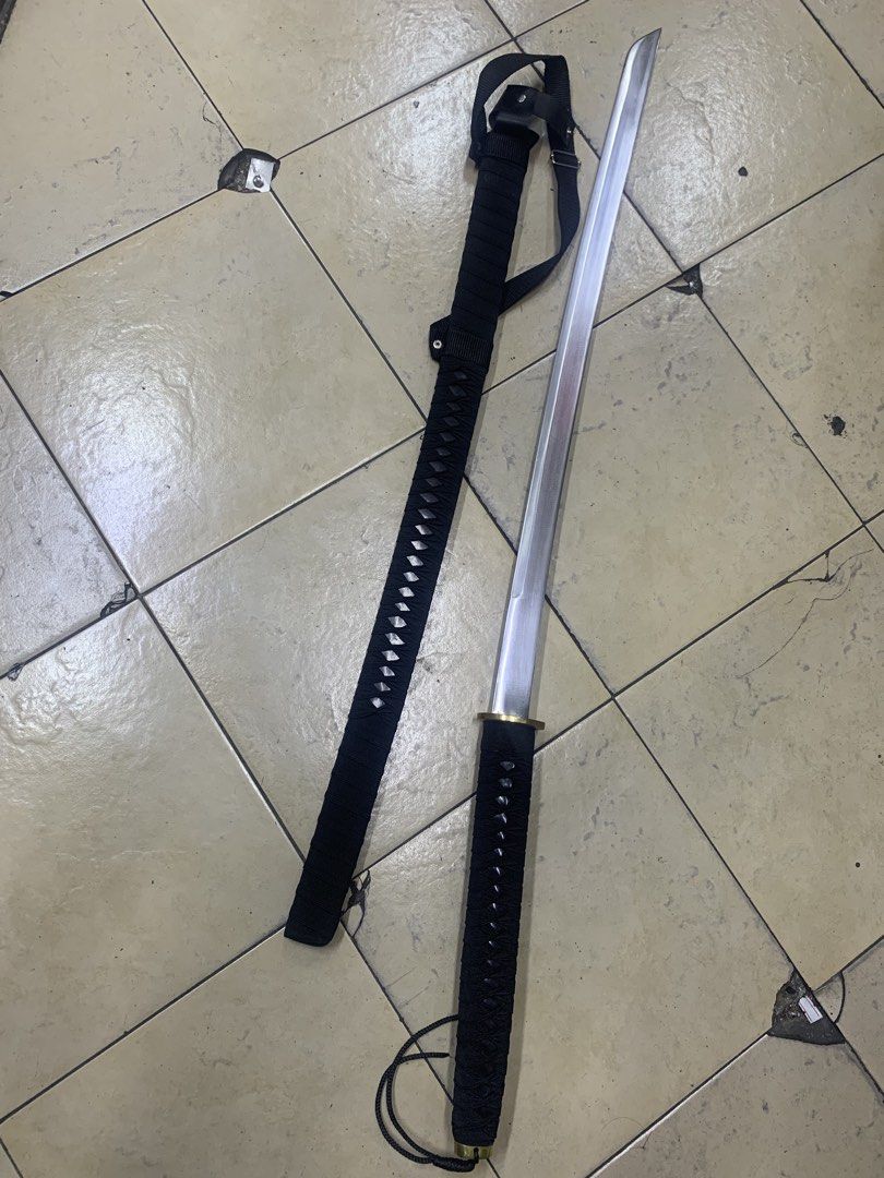 Katana Sword with Scabbard and Strap (Category: Vintage Collectibles) located in Pasig City. Submitted by wild_rex_blaza (Listing ID 1451970761, Image 2). Description: - Black handle katana sword - 33 inches all black, with gold colored plate and leather strap - Silver metal blade - Comes with a black scabbard - Includes an adjustable strap - Ideal for display or collection - Serious buyers only.
