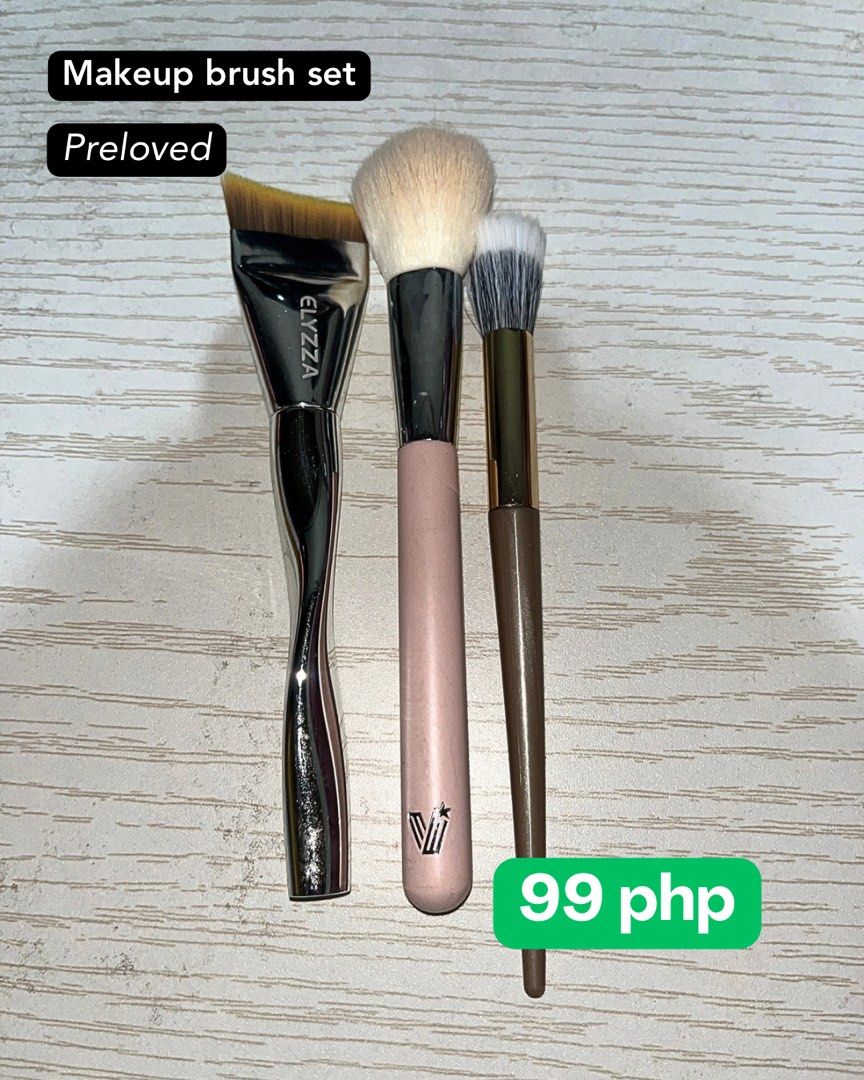 Makeup Brush Set - 3 Pieces (Category: Makeup) located in Manila. Submitted by anncaranto97296 (Listing ID 1452041347, Image 1). Description: - Set of 3 preloved makeup brushes - Includes: Flat foundation brush (with 'ELYZZZA' print), fluffy powder brush (pink handle, 'VI' logo), and a smaller blending brush (brown handle).