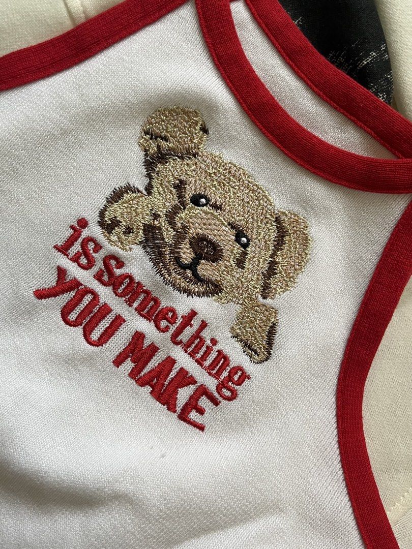 White Teddy Bear Embroidered Crop Top with Red Trim (Category: Others Tops) located in Paranaque City. Submitted by bymuse.co (Listing ID 1452008677, Image 2). Description: - Adorable white crop top - Features a cute teddy bear embroidery with 'is something YOU MAKE' text - Stylish red trim along the neckline and hem - Sleeveless halter design - Perfect for casual outfits or layering - Fits like a size Small.