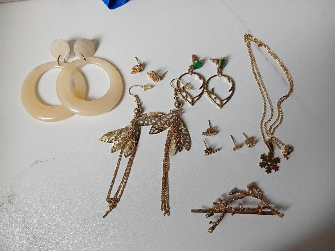 Assorted Gold-Tone Earrings and Necklace Set (Category: Necklaces) located in Mandaluyong City. Submitted by cheshireshoppe (Listing ID 1452137883, Image 1). Description: - Gold-tone jewelry collection - Includes large cream hoop earrings - Dragonfly dangle earrings - Heart-shaped earrings with green accents - Necklace with a snowflake pendant - Assorted small stud earrings - Branch-themed hair clip - Great variety for different looks.