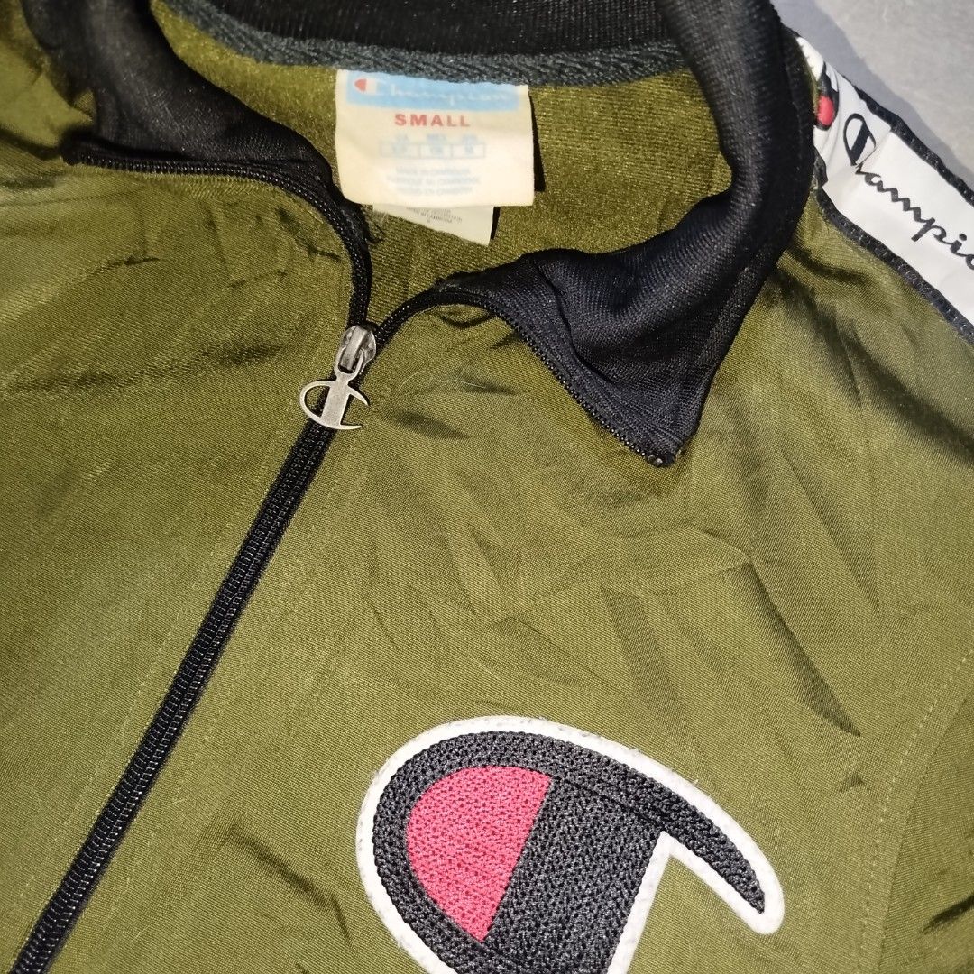 Champion Track Jacket Olive Green with Logo Tape (Category: Coats, Jackets and Outerwear) located in Davao. Submitted by vernoneighty4 (Listing ID 1452263549, Image 3). Description: - Olive green Champion track jacket - Classic Champion C logo on chest - White tape with Champion branding down sleeves - Ribbed cuffs and hem for a snug fit - Full zip closure for easy wear - Ideal for casual outings or athletic activities - small W22 L27.