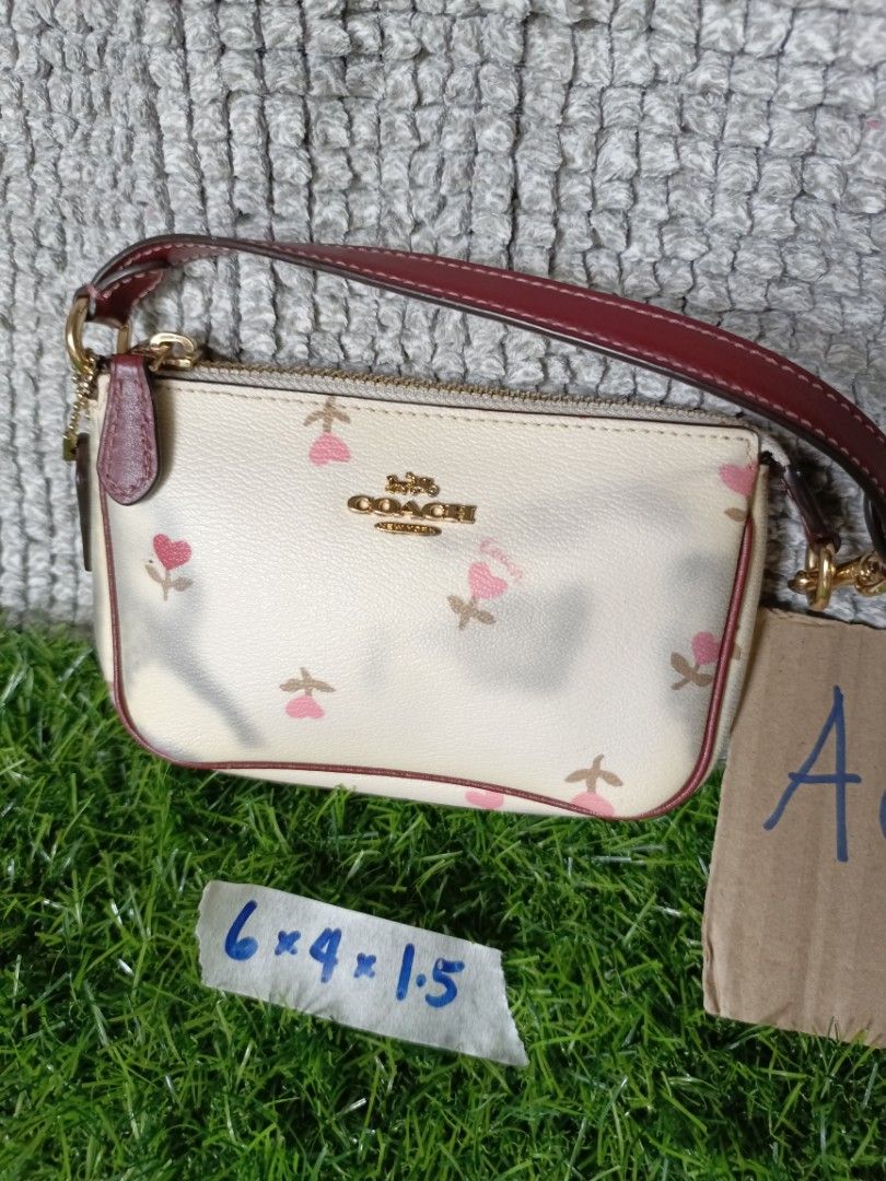 Coach Wristlet Pouch Floral Print (Category: Purses & Pouches) located in Subic. Submitted by addiestrend (Listing ID 1452164095, Image 1). Description: - Cute Coach wristlet pouch - Cream color with a charming pink floral print - Stylish burgundy trim and strap - Features a main zippered compartment - Includes interior card slots for organization - Small and convenient for carrying your essentials Flaw : color transfer seen in the photos (nilabh