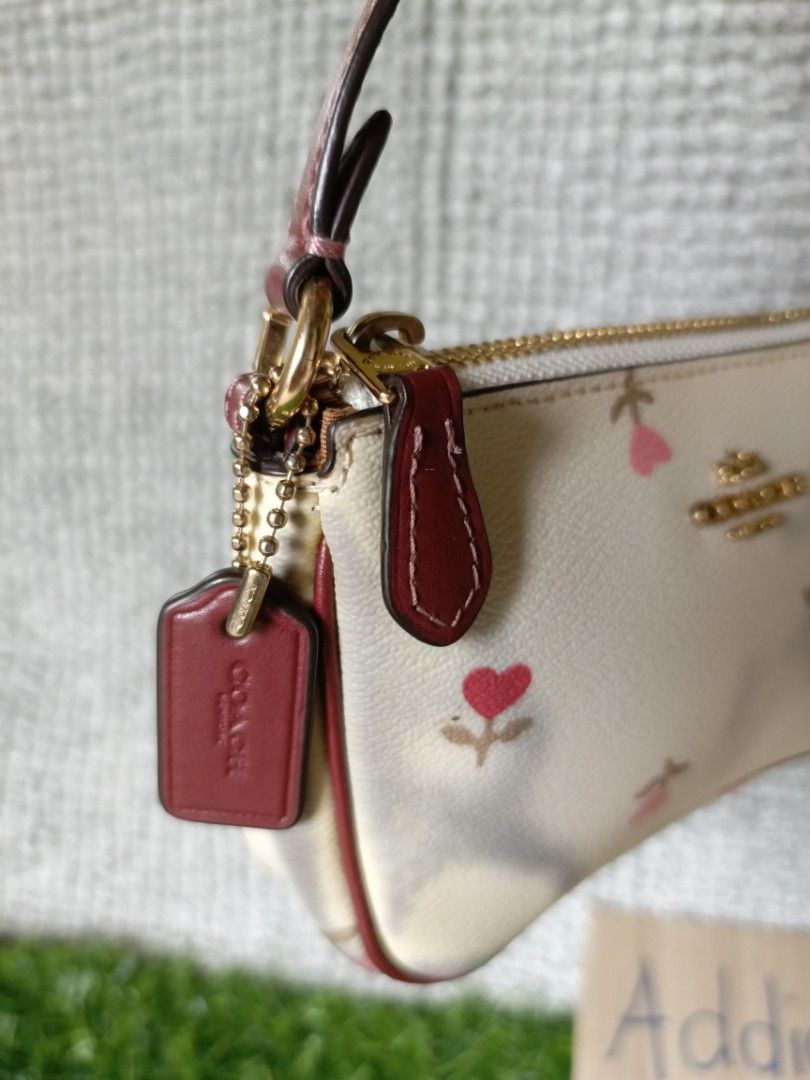 Coach Wristlet Pouch Floral Print (Category: Purses & Pouches) located in Subic. Submitted by addiestrend (Listing ID 1452164095, Image 3). Description: - Cute Coach wristlet pouch - Cream color with a charming pink floral print - Stylish burgundy trim and strap - Features a main zippered compartment - Includes interior card slots for organization - Small and convenient for carrying your essentials Flaw : color transfer seen in the photos (nilabh
