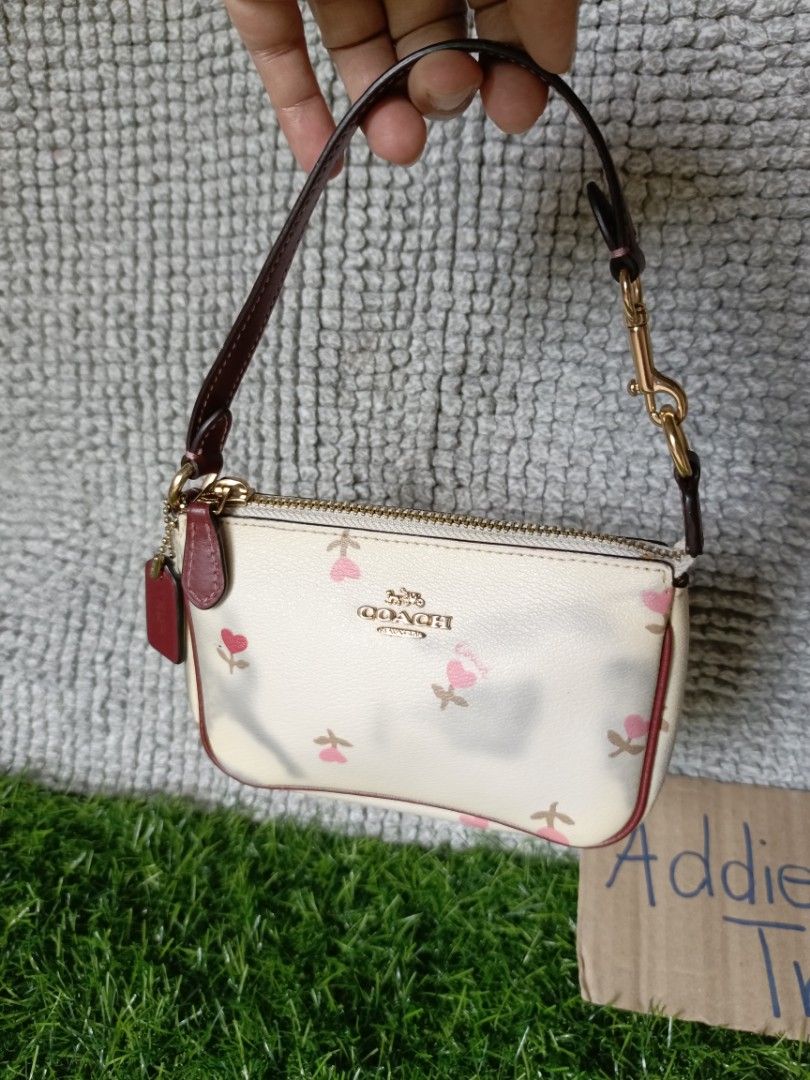 Coach Wristlet Pouch Floral Print (Category: Purses & Pouches) located in Subic. Submitted by addiestrend (Listing ID 1452164095, Image 2). Description: - Cute Coach wristlet pouch - Cream color with a charming pink floral print - Stylish burgundy trim and strap - Features a main zippered compartment - Includes interior card slots for organization - Small and convenient for carrying your essentials Flaw : color transfer seen in the photos (nilabh