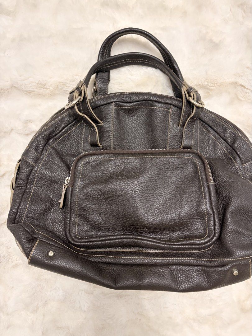 Furla Brown Leather Handbag (Category: Luxury Bags & Wallets) located in Mandaluyong City. Submitted by seafoamint (Listing ID 1443499955, Image 1). Description: Authentic (same silhouette as the ysl muse sac) - Dark brown pebbled leather - Textured finish with contrast stitching details - Convenient zippered pocket on the front - Stylish metal stud accents - Comfortable top handles - Roomy interior for all your essentials Size:width: 15.7inches 