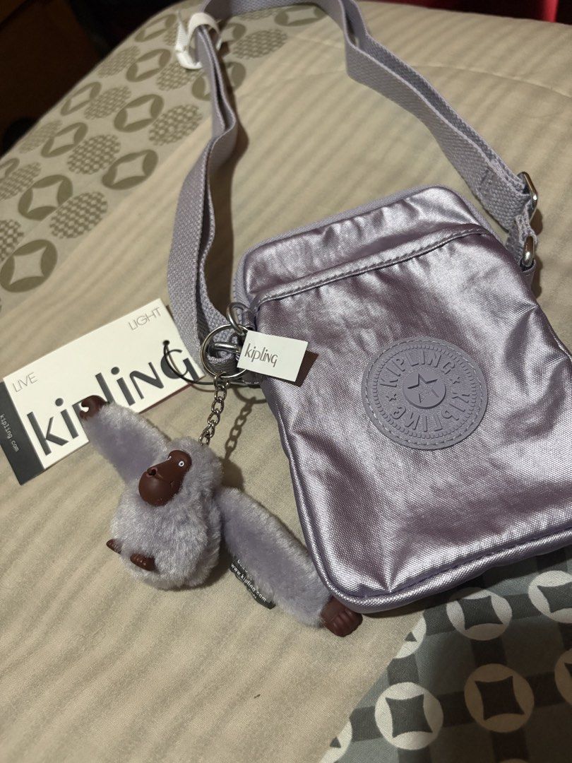 Kipling Metallic Purple Crossbody Bag with Monkey Charm (Category: Cross-body Bags) located in Taguig. Submitted by dvllnv (Listing ID 1452114211, Image 1). Description: - Super cute Kipling crossbody bag - Metallic purple color, very shiny - Includes classic Kipling monkey charm - Adjustable strap for comfortable wear - Ideal for carrying daily essentials - Brand new with tags still attached.