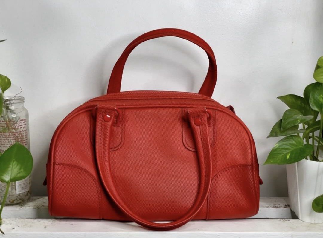 Lacoste Red Boston Bag (Category: Luxury Bags & Wallets) located in Manila. Submitted by TindahanNiLhelay (Listing ID 1452255986, Image 2). Description: - Red Lacoste Boston Bag - Textured material - Zipper closure - Interior zippered pocket - Interior slip pocket - Clean lining - Spacious interior - Great for everyday use.