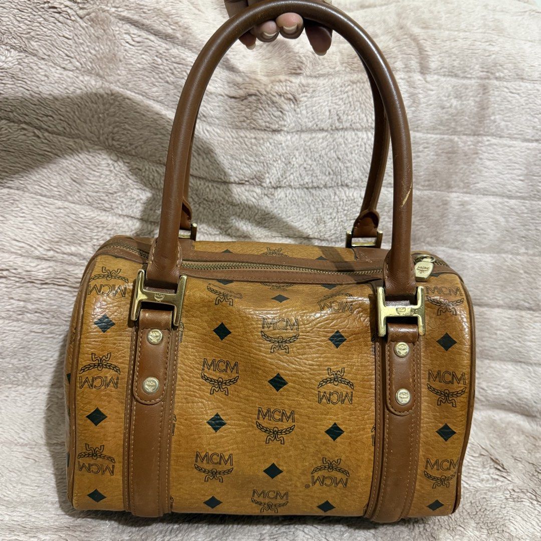 MCM Boston Bag (Category: Luxury Bags & Wallets) located in Bulacan. Submitted by trendsettersquad (Listing ID 1452315257, Image 2). Description: 🏷️ Item Code: BW06 👜 Brand: MCM Boston bag in the iconic Cognac Visetos Monogram 📏 Dimensions: 10 × 7 × 7 in. ✨ Condition: Authentic. Clean interior and exterior. Hardware is complete with normal vintage patina. Sturdy handles. The rubber edge lining (edge paint) has minor flaws due to age and normal
