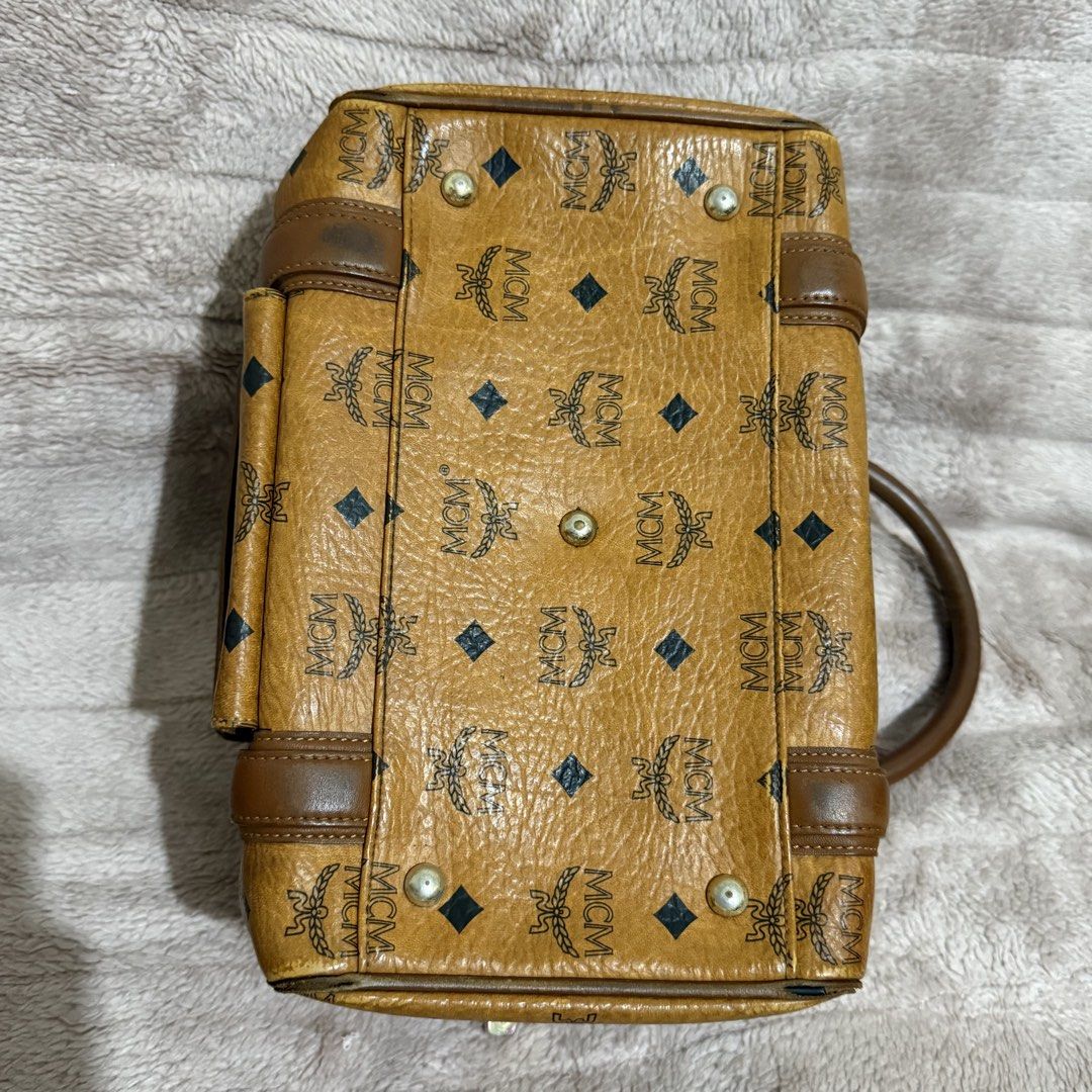 MCM Boston Bag (Category: Luxury Bags & Wallets) located in Bulacan. Submitted by trendsettersquad (Listing ID 1452315257, Image 3). Description: 🏷️ Item Code: BW06 👜 Brand: MCM Boston bag in the iconic Cognac Visetos Monogram 📏 Dimensions: 10 × 7 × 7 in. ✨ Condition: Authentic. Clean interior and exterior. Hardware is complete with normal vintage patina. Sturdy handles. The rubber edge lining (edge paint) has minor flaws due to age and normal