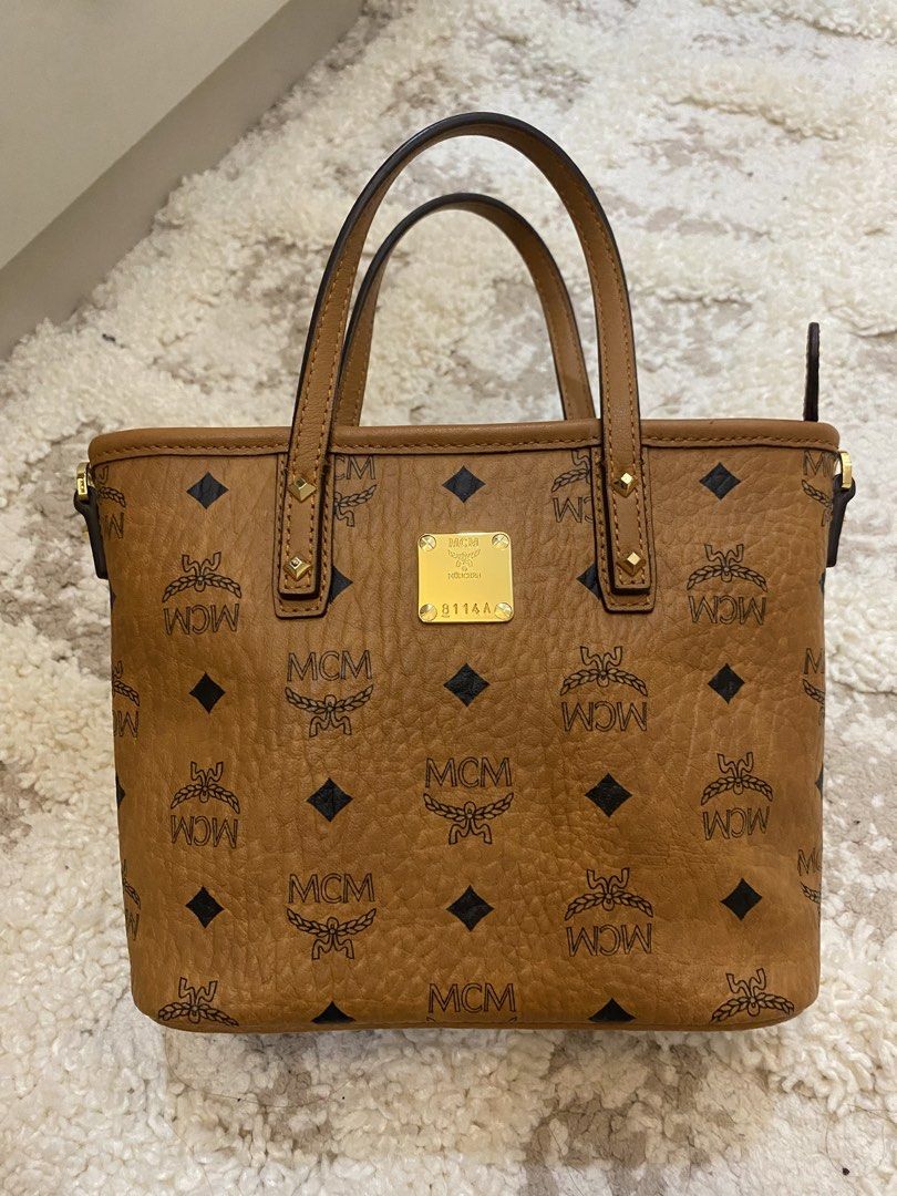 MCM Visetos Mini Tote Bag (Category: Luxury Bags & Wallets) located in Bulacan. Submitted by aksantos10 (Listing ID 1452212605, Image 2). Description: - Classic MCM tote bag - Signature Visetos print (tan brown with black MCM logo) - Gold-tone hardware and MCM logo plate - Top handles .
