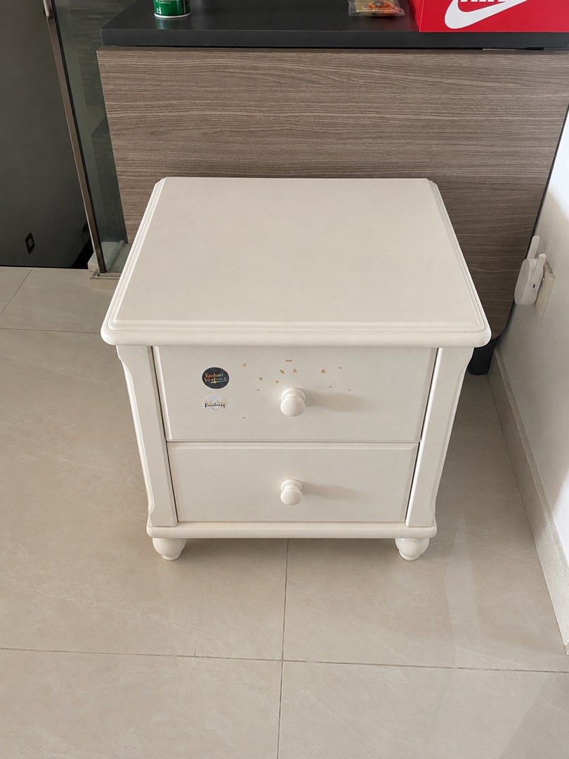 White Solid Wood Two-Drawer Nightstand with Round Knobs (Category: Shelves, Cabinets & Racks) located in Singapore. Submitted by reityz. (Listing ID 1452200194, Image 1). Description: 41.5cm/49.5cm/51.5cm - White solid wood bedside table - Two drawers with easy-open round wooden knobs - Slightly rounded top edge - Classic turned legs - Warm wood tone drawer interiors - Minor marks and dust visible on surface and sides .