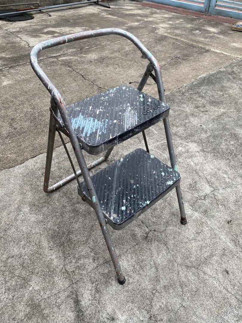 2-Step Metal Step Stool with Handle (Category: Chairs) located in Manila. Submitted by tavorafrancis8096 (Listing ID 1452433201, Image 1). Description: - Sturdy metal construction - Two steps for added height - Convenient handle for extra stability - Shows minor paint splatters from normal use - Folds flat for easy storage - Ideal for reaching high shelves or small DIY tasks.