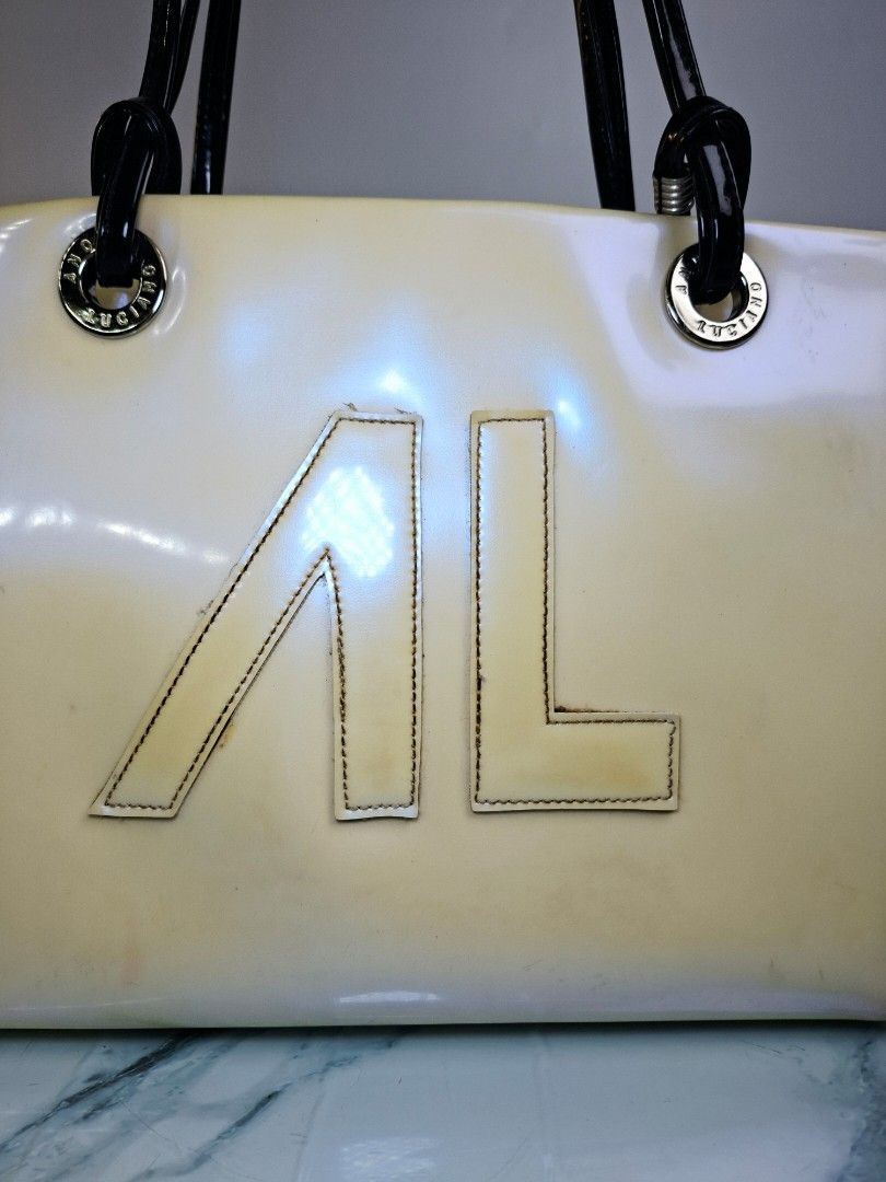 ANDRE LUCIANO Patent Leather Handbag (Category: Tote Bags) located in Pasay City. Submitted by onick_79 (Listing ID 1452349799, Image 3). Description: ​​Chic and stylish cream patent shoulder bag featuring a bold front logo, black patent dual handles, silver hardware, and a fun printed interior lining! ​Brand: Andre Luciano ​Condition: Pre-loved with visible signs of use/color transfer (priced accordingly; please manage expectations and see photo