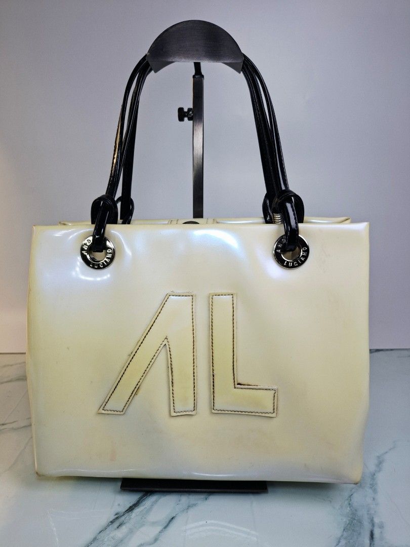 ANDRE LUCIANO Patent Leather Handbag (Category: Tote Bags) located in Pasay City. Submitted by onick_79 (Listing ID 1452349799, Image 1). Description: ​​Chic and stylish cream patent shoulder bag featuring a bold front logo, black patent dual handles, silver hardware, and a fun printed interior lining! ​Brand: Andre Luciano ​Condition: Pre-loved with visible signs of use/color transfer (priced accordingly; please manage expectations and see photo