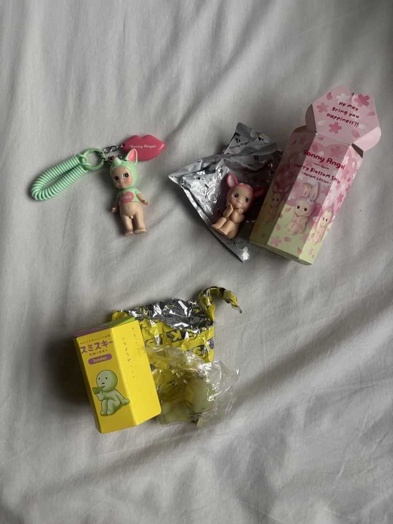 assorted figures (Category: Designer & Blind Box Toys) located in Singapore. Submitted by ana1s (Listing ID 1452429343, Image 1). Description: - Sonny Angel Cherry Blossom Series figure (still in box) - Sonny Angel keychain with pink lip charm - Smiski figure, 'Sunday' edition (in yellow box) - All items are from blind boxes - Great for collectors!.