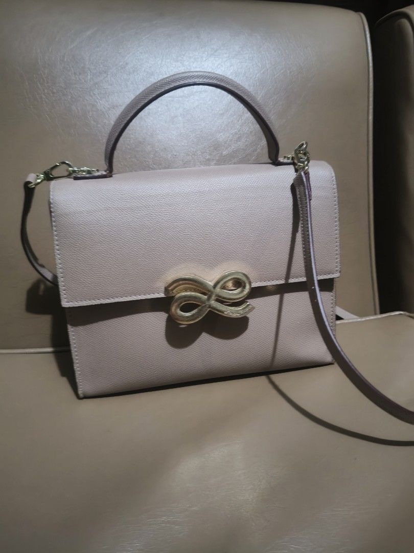 Designer Top Handle Bag with Gold Clasp (Category: Luxury Bags & Wallets) located in Bulacan. Submitted by aichang21 (Listing ID 1452391301, Image 2). Description: - Cute structured handbag - Light pink/beige color - Top handle and detachable shoulder strap - Unique gold bow clasp - Spacious interior for essentials - Versatile for daily use or special occasions.