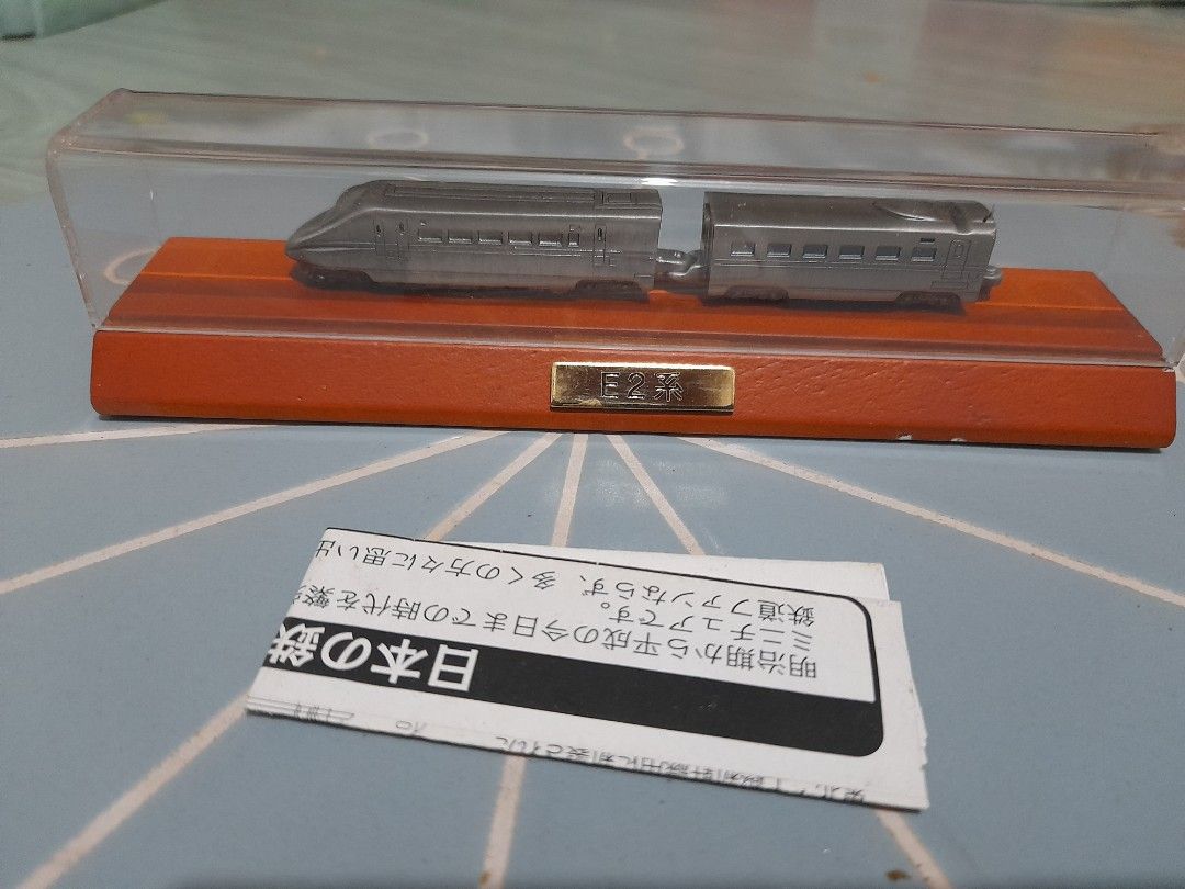 Japan E2 Shinkansen Bullet Train Miniature Model (Category: Vehicle & Diecast Models) located in Bocaue. Submitted by marajapansurplus (Listing ID 1452440324, Image 1). Description: - Miniature model of the Japan E2 Shinkansen bullet train. - Comes displayed on a wooden base with a clear protective case. - Features a small metal plate on the base labeled 'E2'. - Includes a small, authentic Japanese pamphlet. - An excellent collectible for any tra