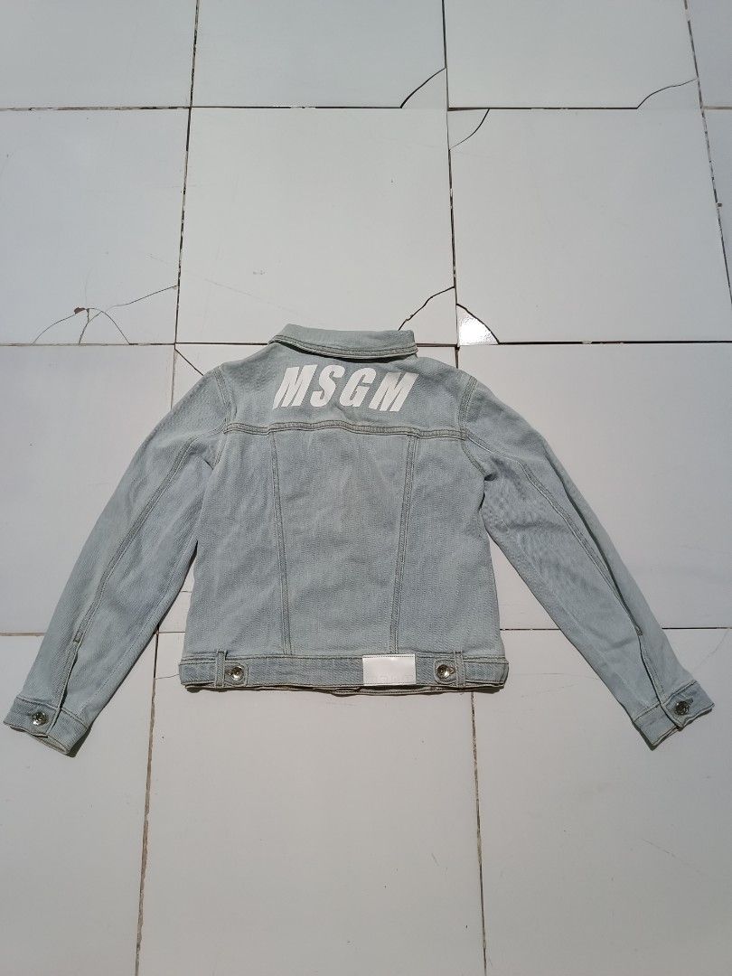 MSG M Kids Light Wash Denim Jacket (Category: Babies & Kids Fashion) located in Barotac Nuevo. Submitted by gray101 (Listing ID 1452445923, Image 3). Description: - MSGM Kids light wash denim jacket - Features iconic MSGM logo printed on the back - Classic button-up front with chest pockets - Made from soft cotton with added stretch for comfort - Size: Tag says Tg. 10 Anni (approximately 10 years old) - Perfect for stylish everyday wear.