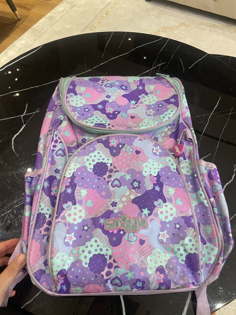 Smiggle Purple Cloud Pattern Backpack (Category: Backpacks) located in Kuala Lumpur. Submitted by chuaali97 (Listing ID 1452421021, Image 2). Description: - Adorable Smiggle backpack with a fun purple cloud and star pattern. - Main compartment for essentials. - Convenient front pocket for quick access. - Side pockets for water bottles or extra storage. - Cute heart-shaped zipper pulls. - Padded shoulder straps for maximum comfort. - Ideal for sch