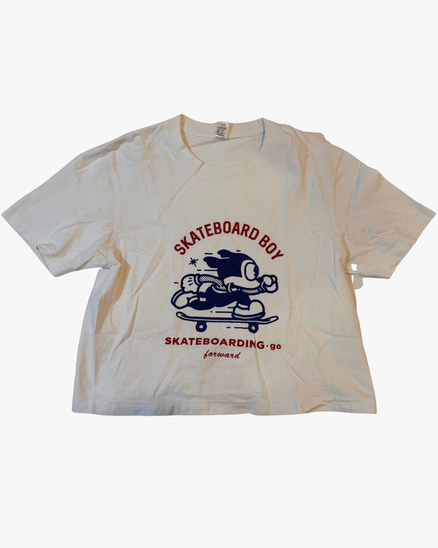 White skateboarding crop top (loose) (Category: Shirts) located in Taguig. Submitted by umiscart (Listing ID 1452480664, Image 1). Description: - White graphic t-shirt - Features a cartoon character on a skateboard - Text: "SKATEBOARD BOY" and "SKATEBOARDING.GO forward" - Short sleeves - Crew neck - Ideal for casual wear.