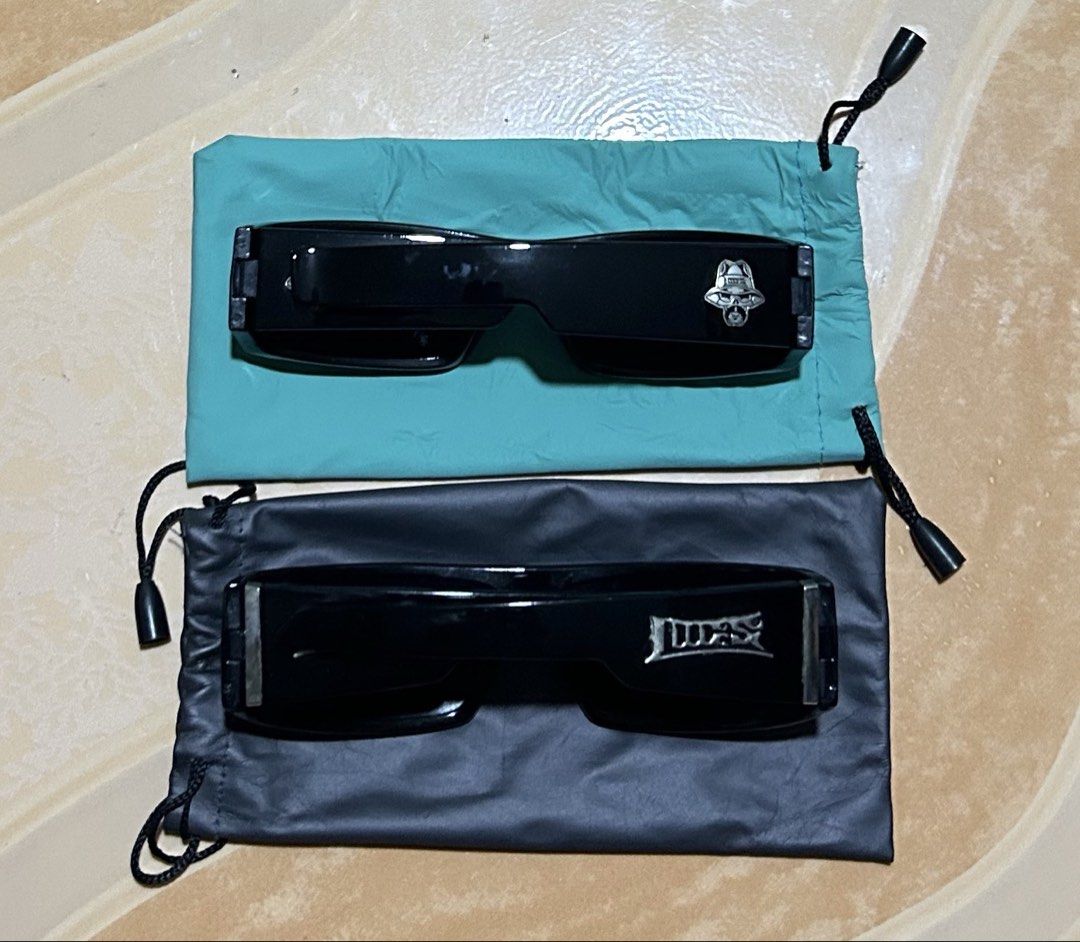 Black Sunglasses with Pouches (Category: Sunglasses & Eyewear) located in Manila. Submitted by dcoolest (Listing ID 1452652621, Image 2). Description: - Two pairs of stylish black sunglasses. - One pair has a unique bell-shaped logo. - The second pair features a 'LUCAS' logo. - Both sunglasses come with protective drawstring pouches. - One pouch is a vibrant teal color. -take all -2 pcs - The other pouch is classic black. - Ideal for protecting y