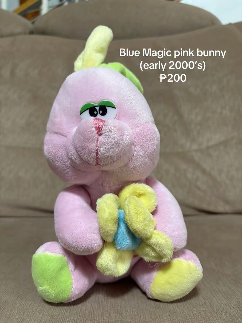 Blue Magic pink bunny plush toy (early 2000's) (Category: Plushies & Soft Toys) located in Cavite. Submitted by marissa0_0 (Listing ID 1452685221, Image 1). Description: - Adorable pink bunny plush toy from Blue Magic. - Early 2000s vintage collectible. - Features a yellow flower with a blue center. - Cute green eyes and a pink nose. - Ideal for collectors or as a charming decoration..