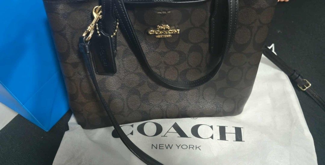 Coach Signature Canvas Tote Bag (Category: Luxury Bags & Wallets) located in Manila. Submitted by say14 (Listing ID 1452607741, Image 1). Description: Coach tote bag in signature brown and black print. Gold hardware details. Includes a black leather hangtag. Comes with a Coach dust bag. Great for everyday use..
