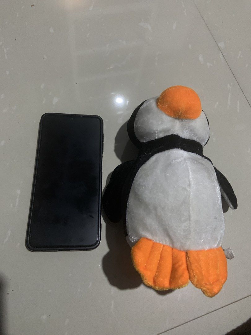 Cute Penguin Plush Toy (Category: Plushies & Soft Toys) located in Cavite. Submitted by krydeclutter (Listing ID 1452599540, Image 3). Description: - Soft and cuddly penguin plush toy - Features an orange beak and feet - Ideal for children or as a charming decoration - Approximately the size of a smartphone - Eager to find its new loving home!.