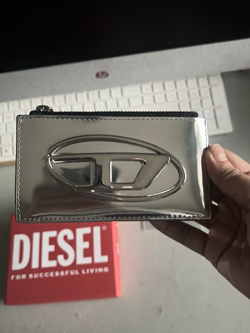Diesel Card Holder In Mirror Leather Silver (Category: Wallets & Card holders) located in Makati City. Submitted by heybyemystuff (Listing ID 1452570110, Image 3). Description: - Brand: Diesel - Material: Silver mirror leather - Closure: Zipper - Includes: Original box and tags - Features: Keeps cards organized, sleek and stylish design Bought in Japan.