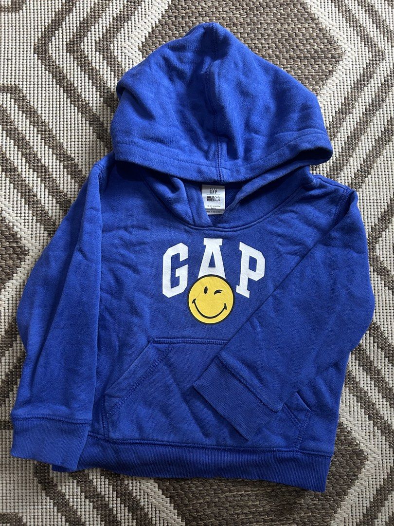 Gap Blue Hoodie with Smiley Face Graphic (Category: Babies & Kids Fashion) located in Santa Rosa. Submitted by lovedbydane (Listing ID 1452517571, Image 1). Description: - Blue Gap hoodie for kids - Size: 18-24 months - Features classic Gap logo with a cute winking smiley face graphic - Includes a front pocket and hood - Ideal for everyday wear.