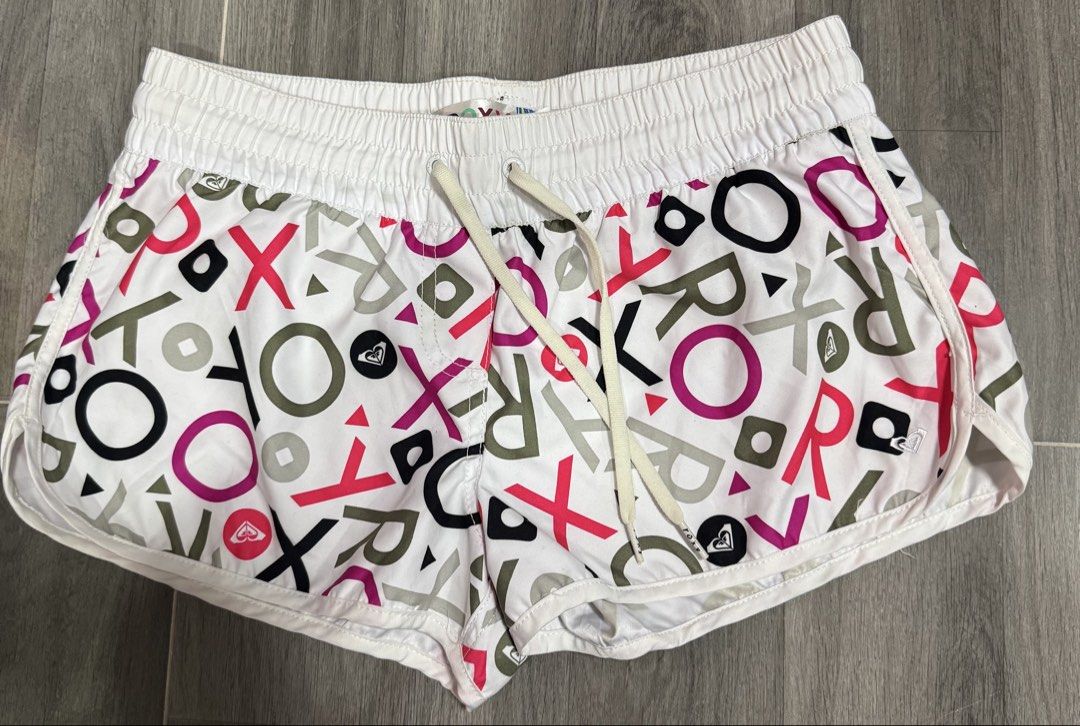 Roxy White Multi-Color Logo Print Board Shorts Size M (Category: Shorts) located in Las Pinas. Submitted by vanethneth (Listing ID 1452640628, Image 1). Description: - Roxy Board Shorts - Size: Medium (M) - Color: White with all-over logo print - Print Colors: Pink, purple, black, grey - Features: Drawstring waist, back zippered pocket, elastic waistband for comfort - Ideal for: Beach days, casual outings.