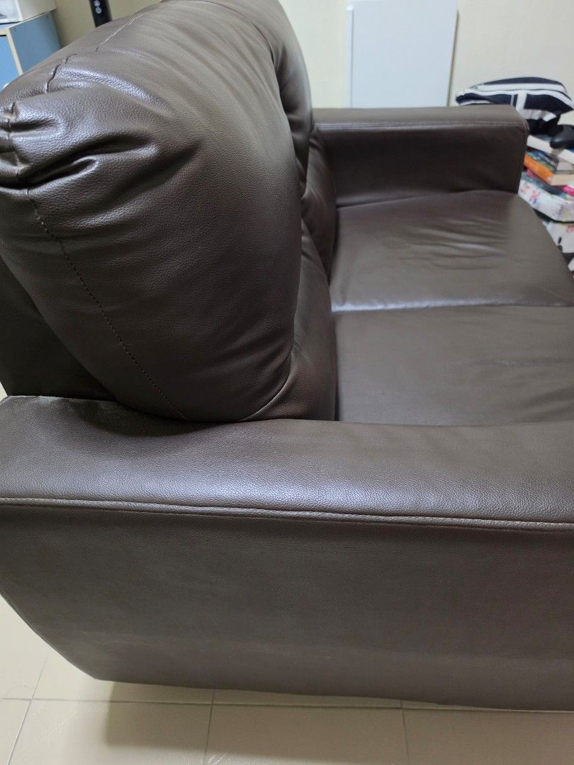 Sofa (Category: Sofas) located in Singapore. Submitted by bluesws (Listing ID 1452666487, Image 3). Description: - 2-seater sofa - Color: Brown - Material: Faux leather - Design: Classic, plush cushions - Condition: Good - Location: Bishan This sofa has been placed in our guest room and was rarely used, so it's still very clean and in good overall condition. The cushions are firm and comfortable, with no tears, peeling, or major scratches. Condit