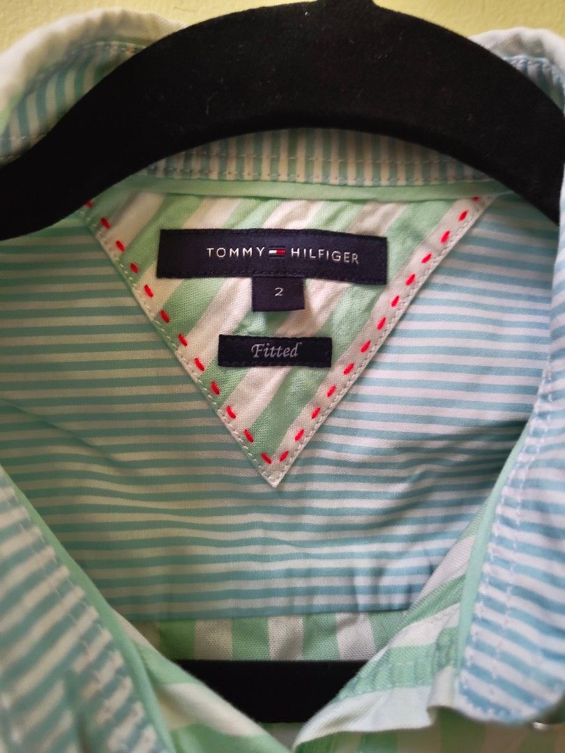 Tommy Hilfiger Striped Fitted Shirt Size 2 (Category: Shirts) located in Quezon City. Submitted by teleh.reyes (Listing ID 1452523774, Image 3). Description: - Tommy Hilfiger short-sleeved shirt - Size: 2 (fitted style) - Color: Light green and white stripes - Features: Button-down front, small Tommy Hilfiger flag detail on shoulder - Versatile: Great for casual or smart-casual outfits.