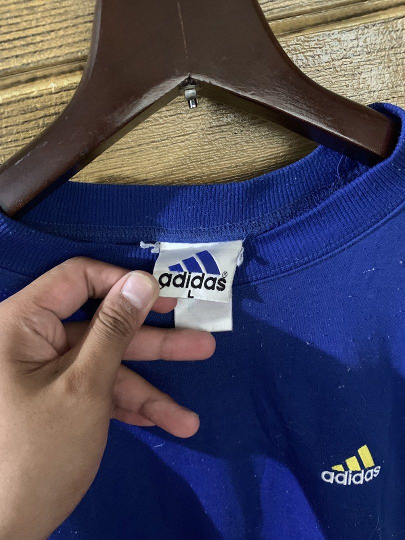 Vintage adidas sweatshirt (Category: Coats, Jackets and Outerwear) located in Valenzuela. Submitted by Caloooy (Listing ID 1452660801, Image 3). Description: Blue vintage Adidas sweatshirt with a small logo on the front and a larger logo on the back. Features a crew neck and long sleeves. The size is Large. The sweatshirt is a vibrant blue color. The Adidas logo is yellow. For 500+sf.
