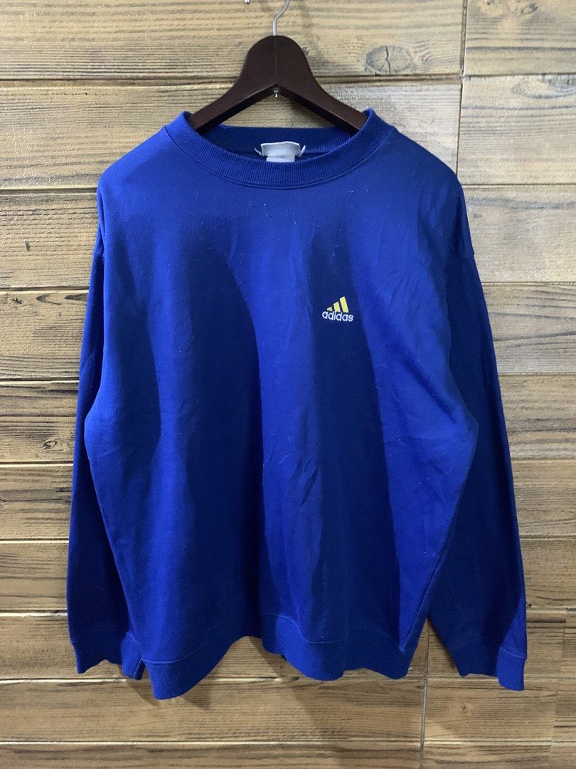 Vintage adidas sweatshirt (Category: Coats, Jackets and Outerwear) located in Valenzuela. Submitted by Caloooy (Listing ID 1452660801, Image 1). Description: Blue vintage Adidas sweatshirt with a small logo on the front and a larger logo on the back. Features a crew neck and long sleeves. The size is Large. The sweatshirt is a vibrant blue color. The Adidas logo is yellow. For 500+sf.