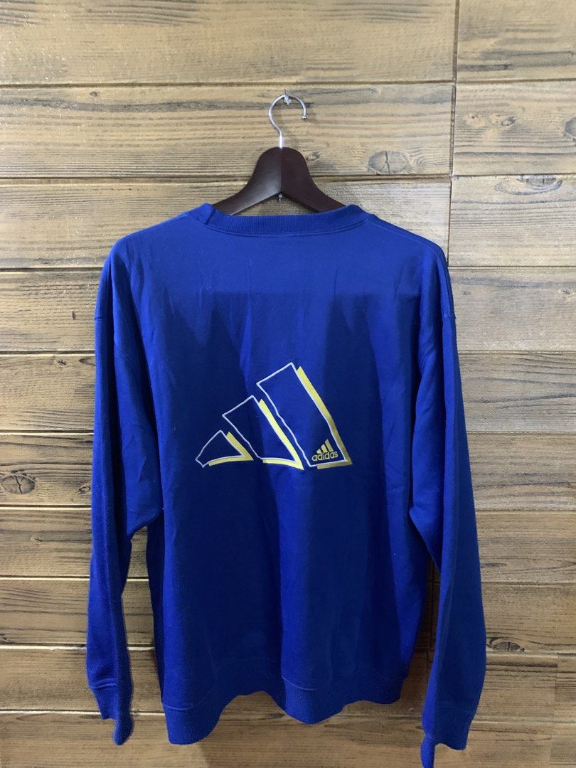 Vintage adidas sweatshirt (Category: Coats, Jackets and Outerwear) located in Valenzuela. Submitted by Caloooy (Listing ID 1452660801, Image 2). Description: Blue vintage Adidas sweatshirt with a small logo on the front and a larger logo on the back. Features a crew neck and long sleeves. The size is Large. The sweatshirt is a vibrant blue color. The Adidas logo is yellow. For 500+sf.