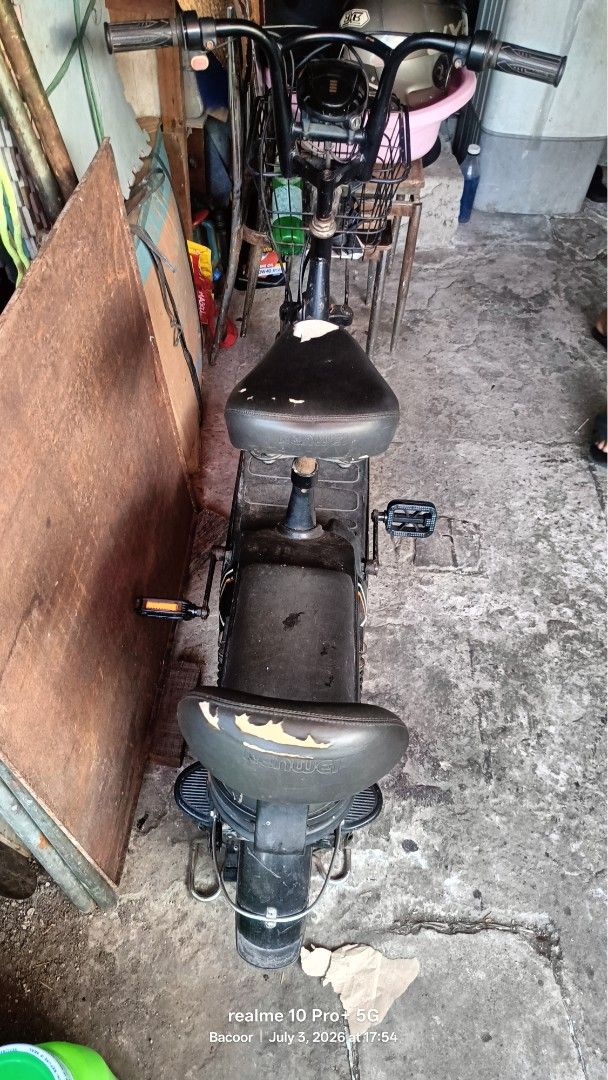 Black Electric Bicycle with Basket (Category: Bicycles) located in Bacoor. Submitted by missyoujohnie16292009.gokgok (Listing ID 1447386397, Image 2). Description: - Black electric bicycle - Includes a front basket for storage - Pedals are visible - Black seat with some signs of wear - Ideal for short neighborhood trips - Ready for its next owner.