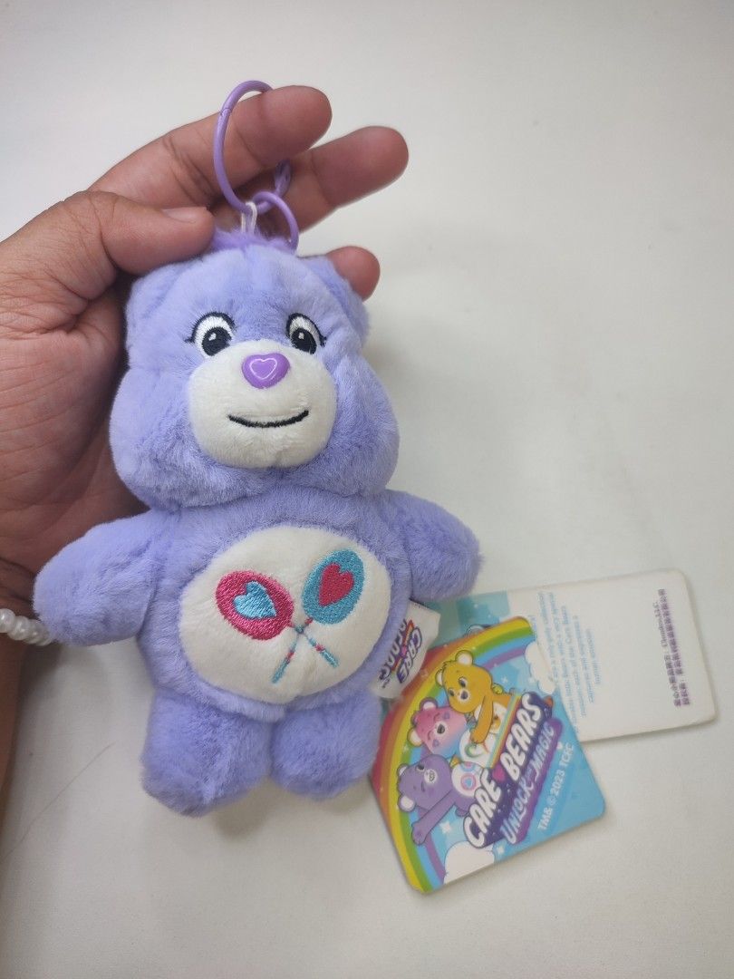 Care Bears Unlock the Magic Plush Keychain (Category: Plushies & Soft Toys) located in Manila. Submitted by epicmountain-f20453 (Listing ID 1447354083, Image 1). Description: - Adorable purple Care Bear plush keychain. - Features the classic belly badge with two lollipops. - Comes with original tags attached. - Ideal for decorating bags or attaching to keys. - A fun collectible from the Care Bears Unlock the Magic series..