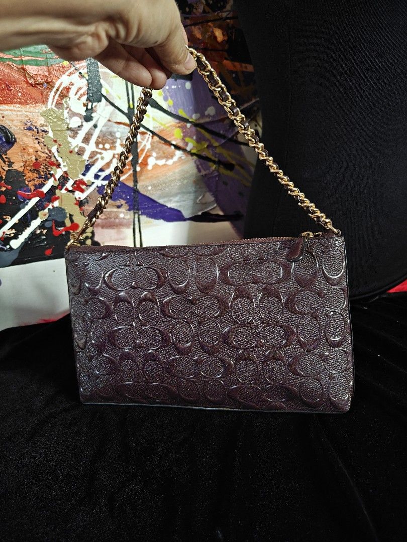 Coach Embossed Signature Cluch with Chain (Category: Luxury Bags & Wallets) located in Las Pinas. Submitted by liezel49 (Listing ID 1447307160, Image 3). Description: Chic Maroon Coach clutch with embossed C logo. Features a gold chain strap and secure zipper closure. Perfect for nights out. Measures 9" W x 5" H. Clean inside and out, includes Coach hangtag..
