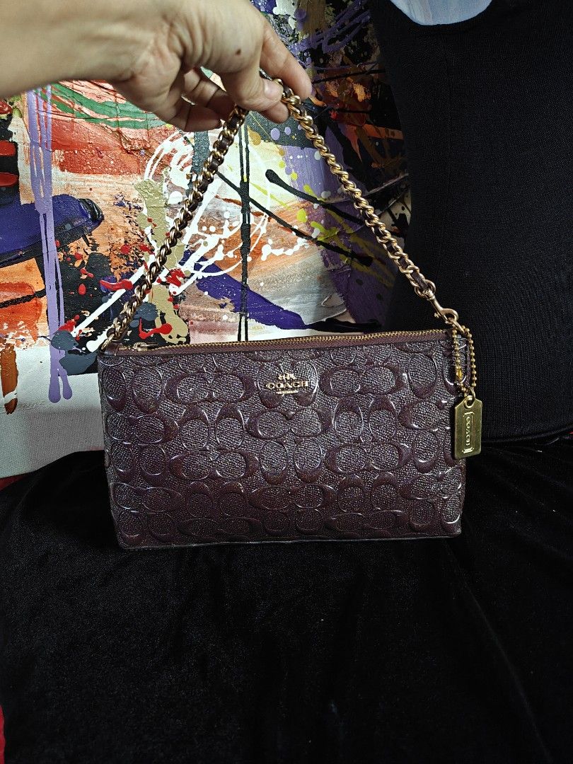 Coach Embossed Signature Cluch with Chain (Category: Luxury Bags & Wallets) located in Las Pinas. Submitted by liezel49 (Listing ID 1447307160, Image 2). Description: Chic Maroon Coach clutch with embossed C logo. Features a gold chain strap and secure zipper closure. Perfect for nights out. Measures 9" W x 5" H. Clean inside and out, includes Coach hangtag..