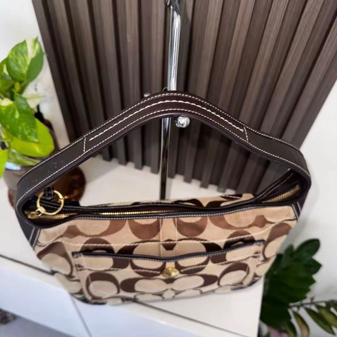 Coach Ergo (Category: Luxury Bags & Wallets) located in Los Banos. Submitted by vvvintiquecollectives (Listing ID 1447327177, Image 2). Description: - Classic Coach hobo bag - Signature monogram canvas with dark brown leather trim - Front pocket with gold-tone clasp - Top zipper closure - Timeless design for everyday use - Comes with Coach hang tag - Negotiable for sure buyers .